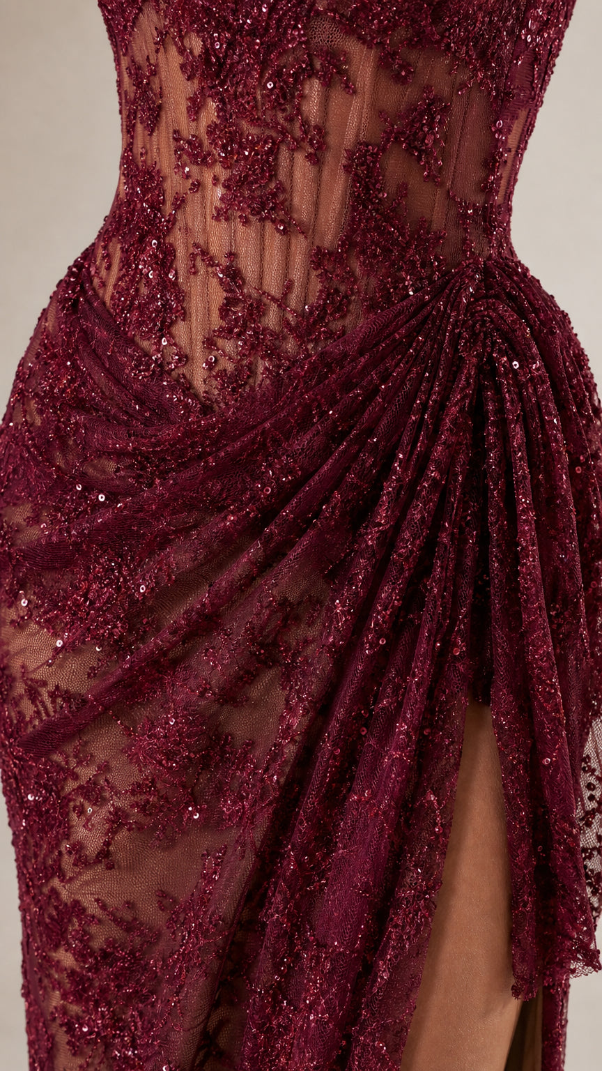 Close-up detail of lace embroidery and draped high slit on burgundy dress