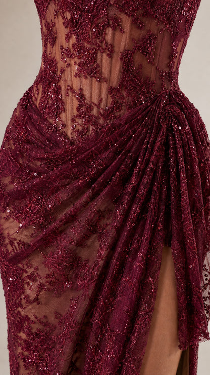 Close-up detail of lace embroidery and draped high slit on burgundy dress