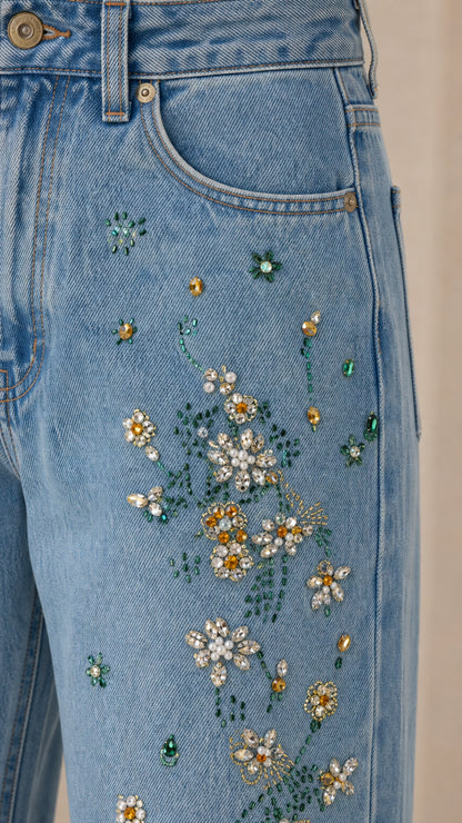 Close-up detail of rhinestone and bead floral embroidery on light blue denim