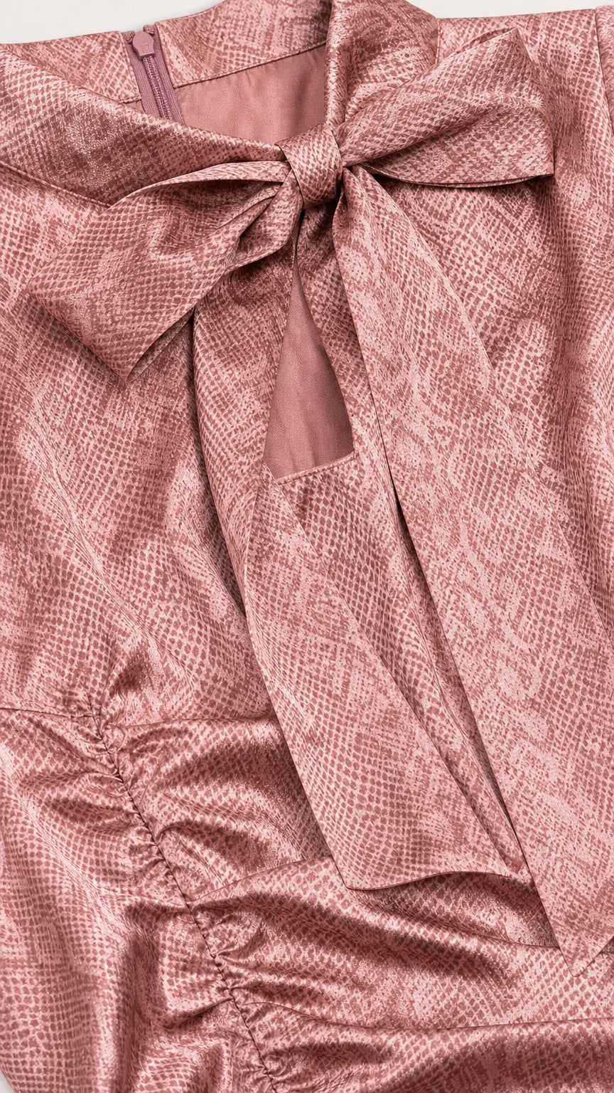 Close-up detail of bow tie neckline, keyhole cutout, and snakeskin texture in dusty rose