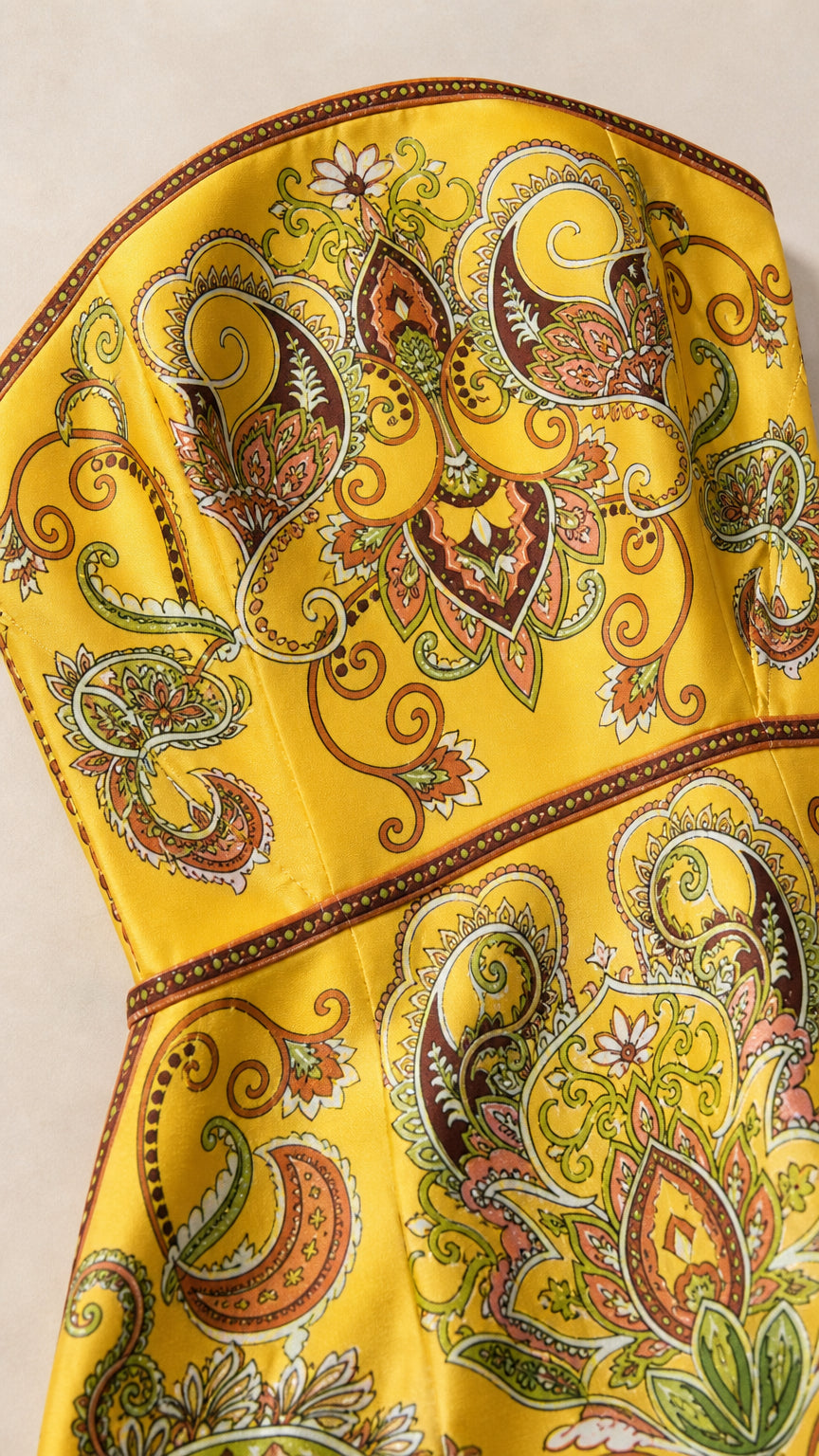 Close-up detail of fabric and pattern on yellow paisley dress