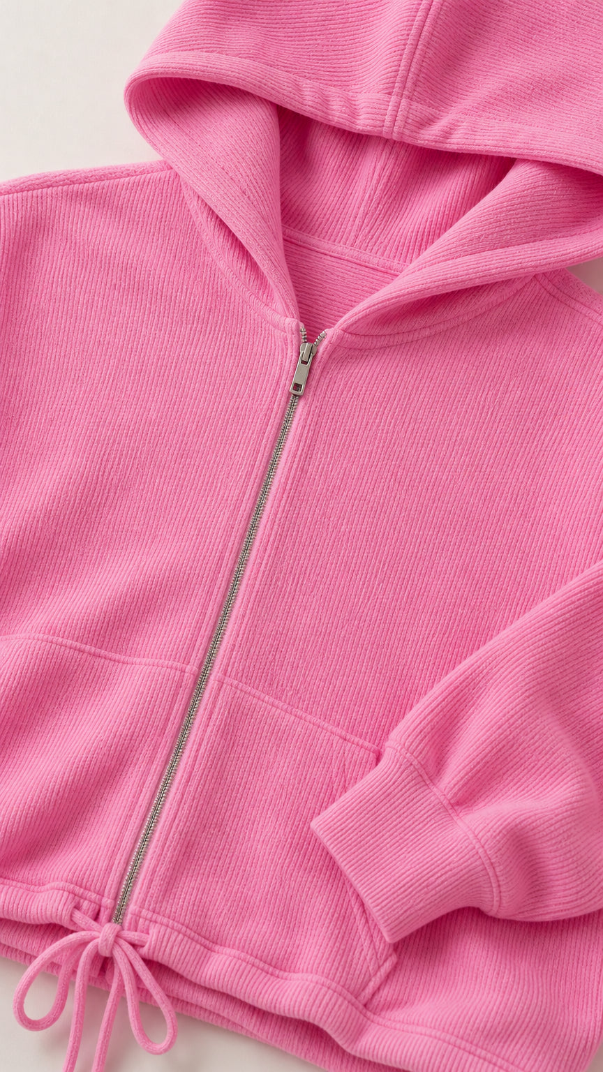Close-up detail of pink textured ribbed knit fabric, front metal zipper, and drawstring hem