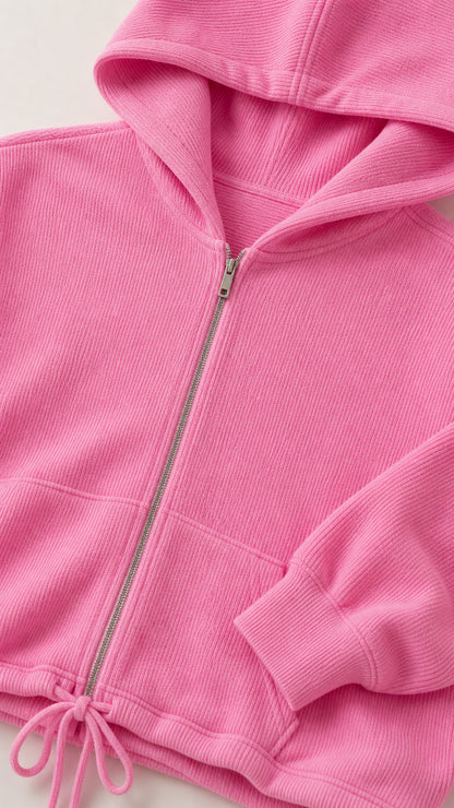 Close-up detail of pink textured ribbed knit fabric, front metal zipper, and drawstring hem