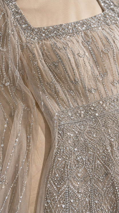 Close-up of intricate silver beadwork and square neckline on champagne mesh dress