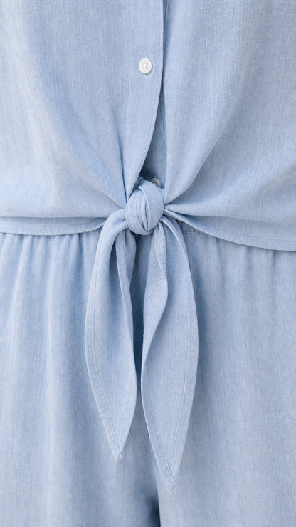 Closeup of tie waist and button placket on light blue jumpsuit