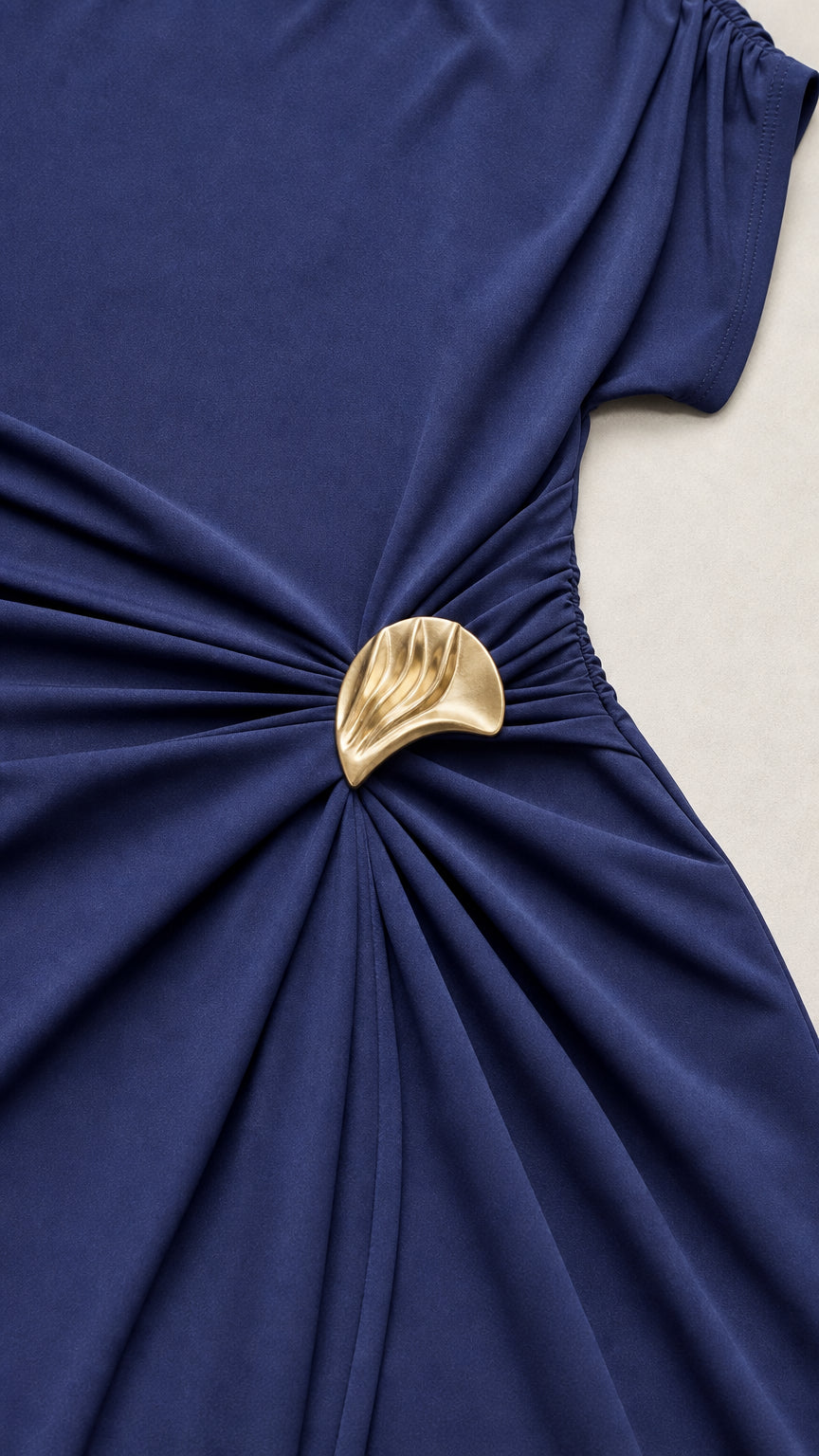 Close-up of gold-tone waist hardware and ruching detail on navy dress