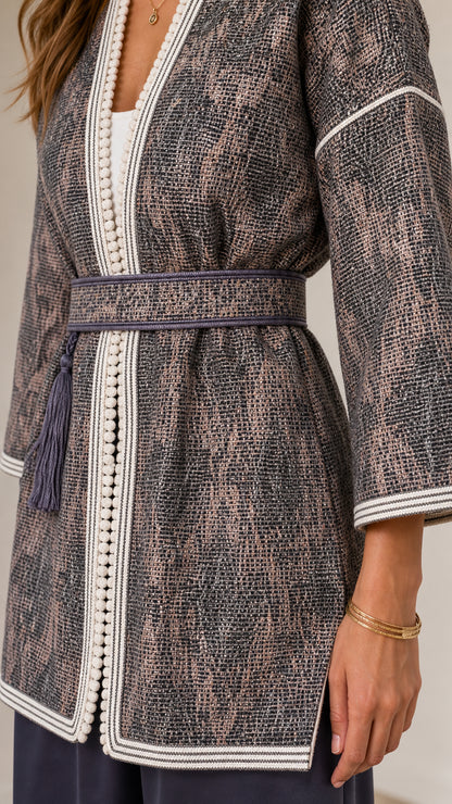 Close-up detail of textured jacquard fabric, braided trim, and tassel belt in Slate Grey