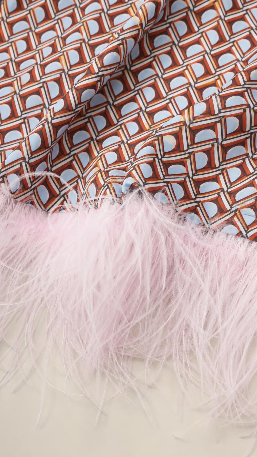 Close-up detail of geometric fabric pattern and pink feather trim