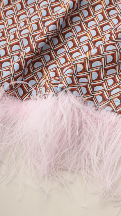 Close-up detail of geometric fabric pattern and pink feather trim