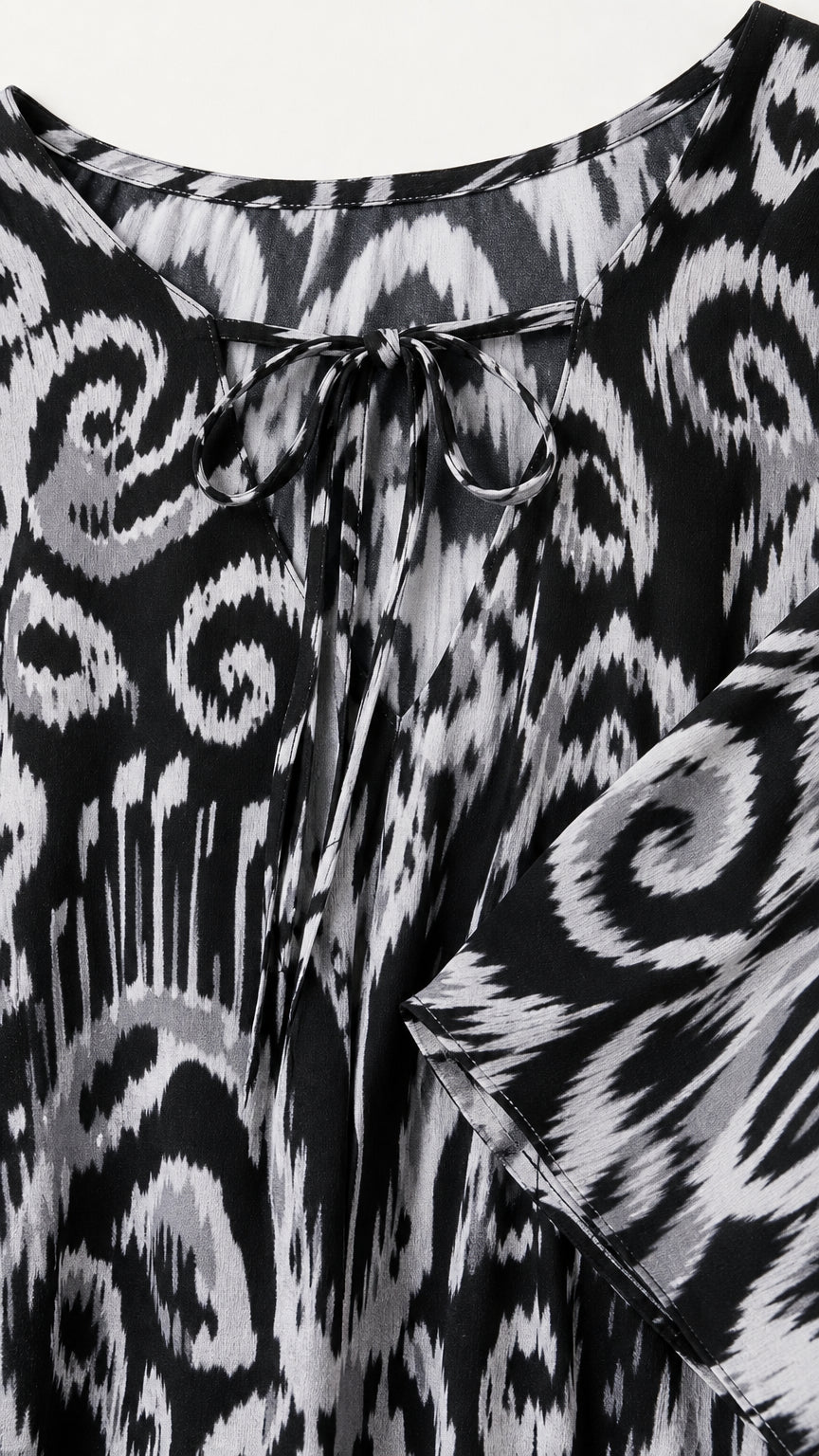 Close-up detail of front tie-neck closure and ikat pattern on black kaftan dress