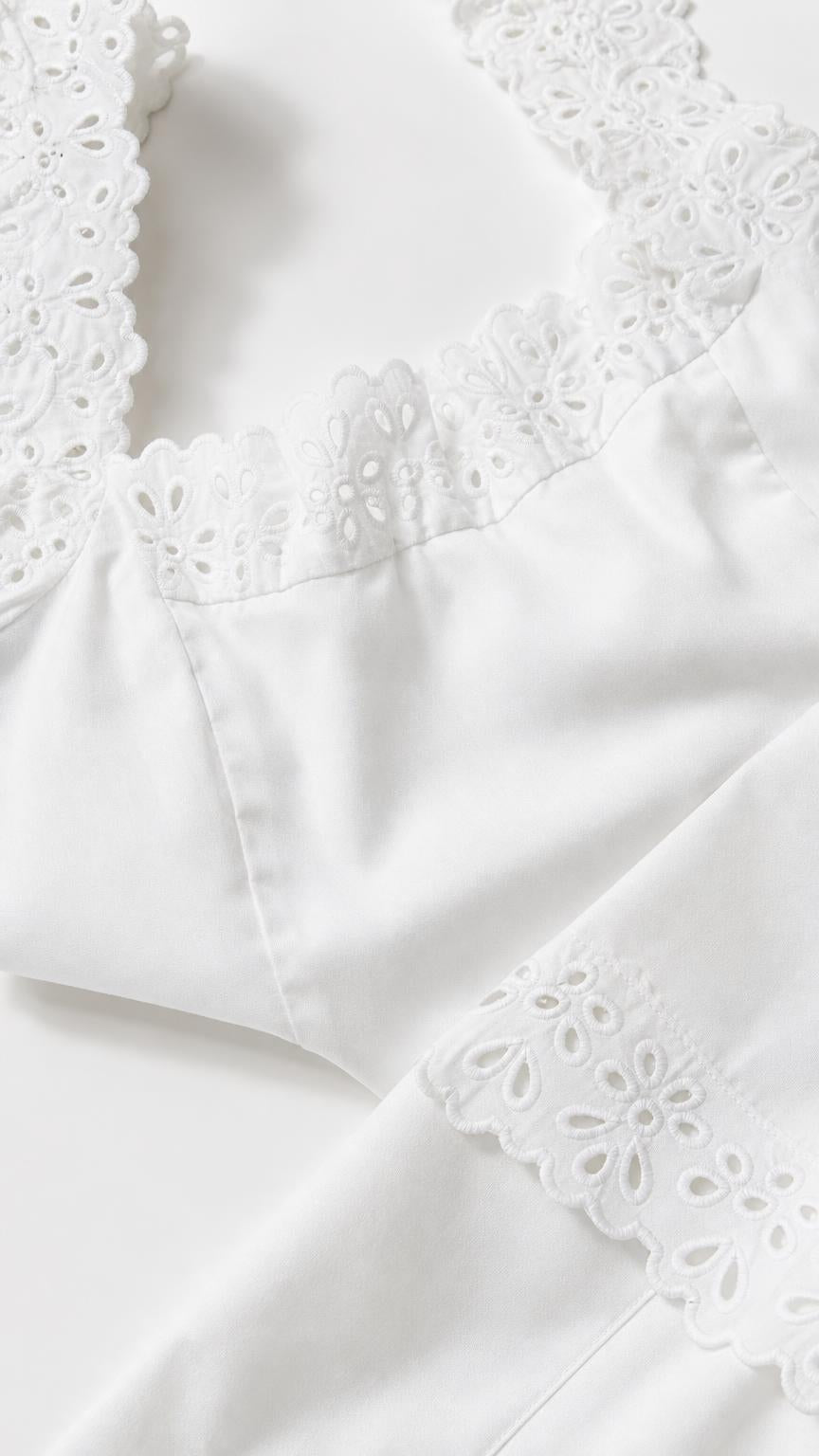 Close-up detail of white eyelet embroidery and scalloped trim