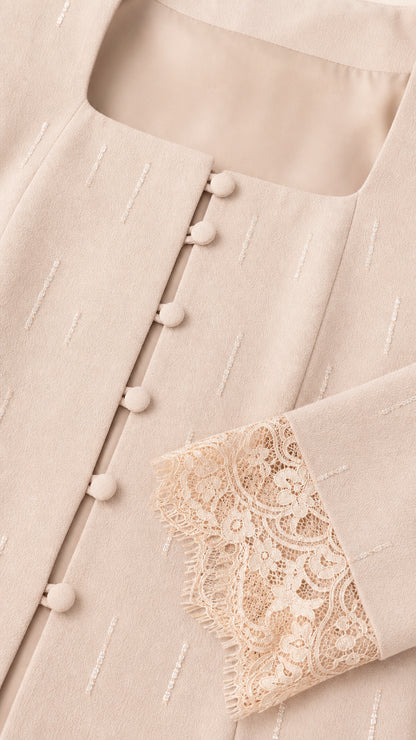 Close-up detail of champagne suit jacket showing square neck, buttons, and lace cuffs