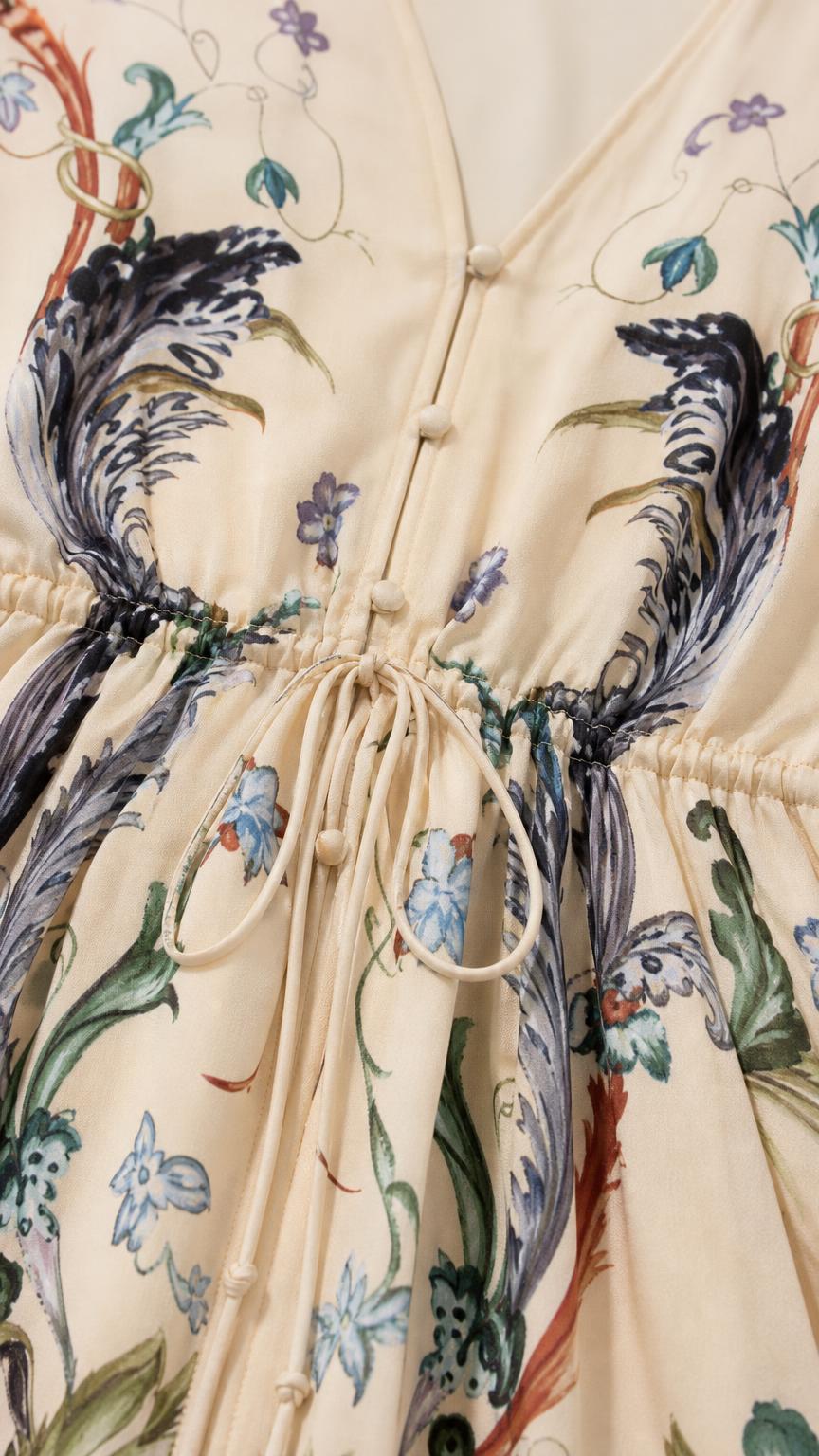 Close up of V-neck and drawstring waist on cream maxi dress