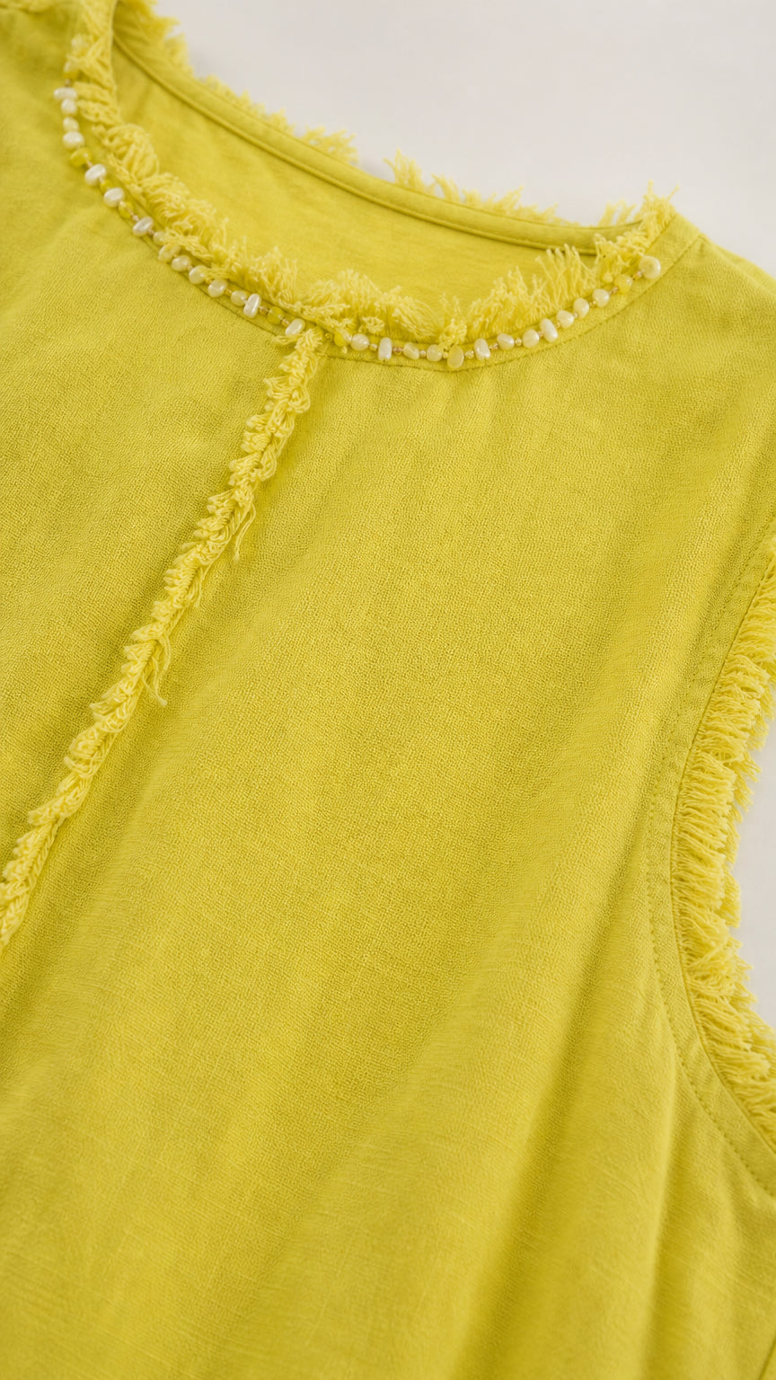 Close-up of beaded neckline and frayed trim on chartreuse dress