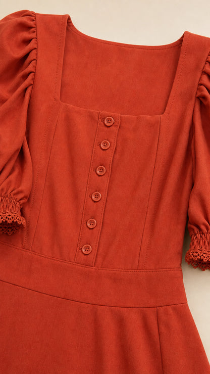 Close-up detail of rust dress bodice with buttons and square neckline