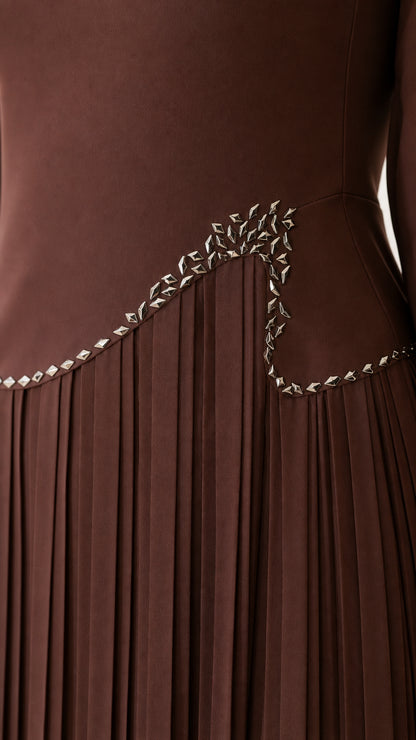Close-up detail of the rhinestone embellishment and accordion pleats on the brown dress