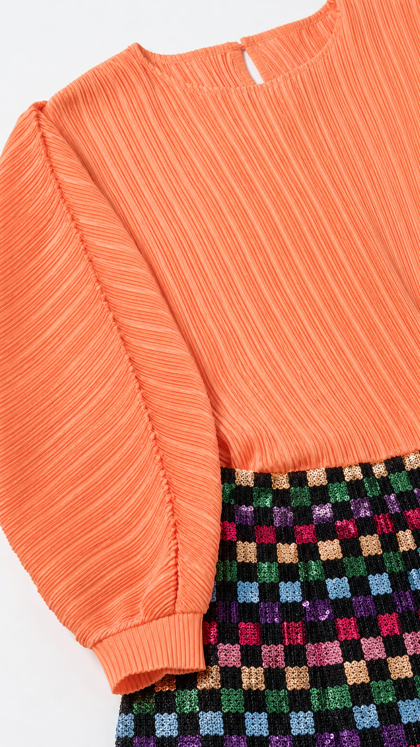Close-up detail of pleated orange fabric and sequin checkered skirt