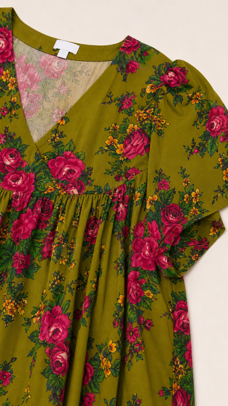 Close-up detail of V-neckline, shirring, and rose floral pattern on olive green fabric