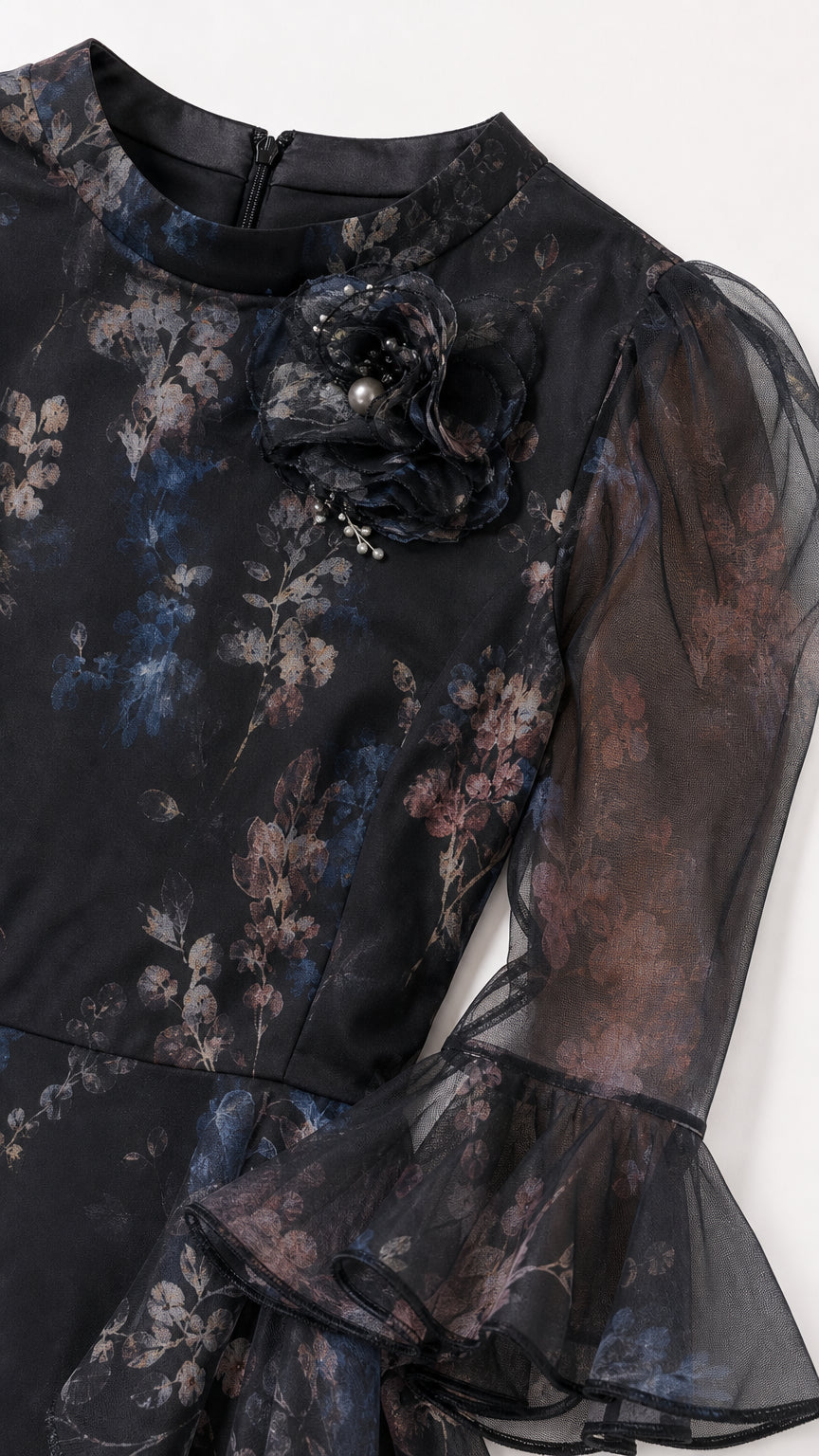 Close-up detail of neckline, 3D floral corsage, and sheer flared cuff on black floral dress