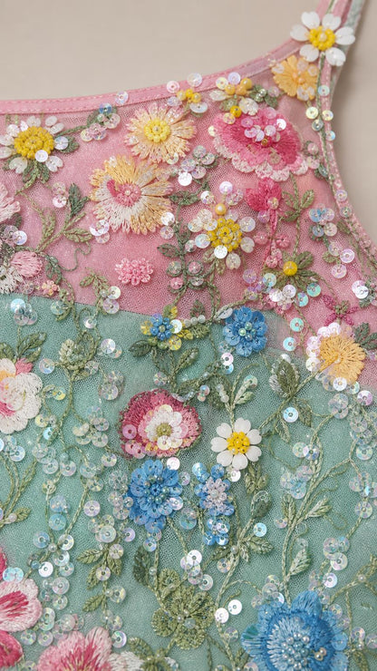 Close-up detail of multi-color floral embroidery and sequins on mint green mesh