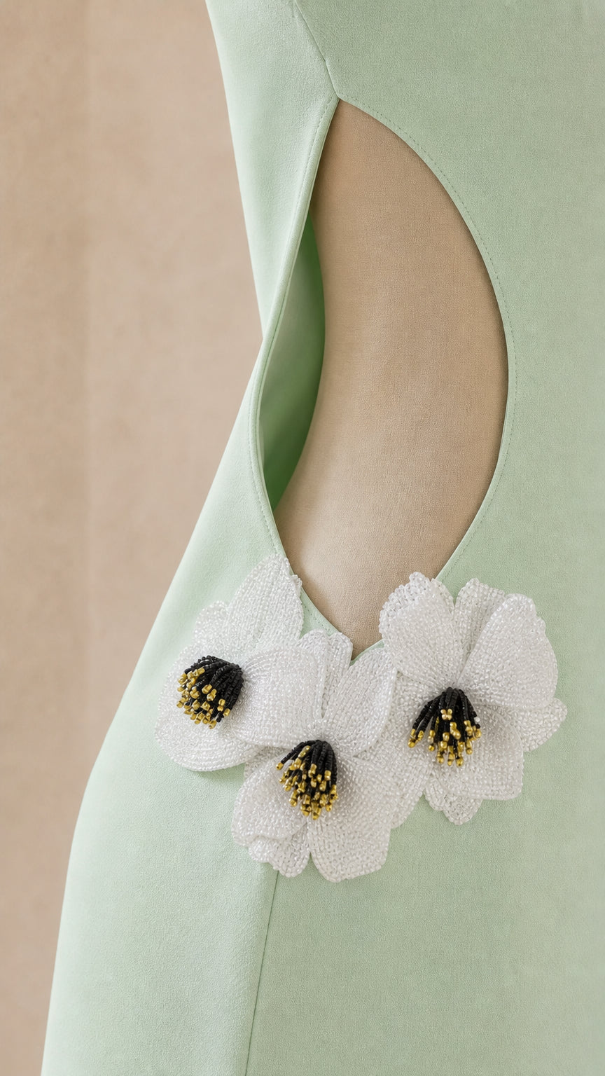 Close-up of side cutout and beaded white floral applique on sage green dress