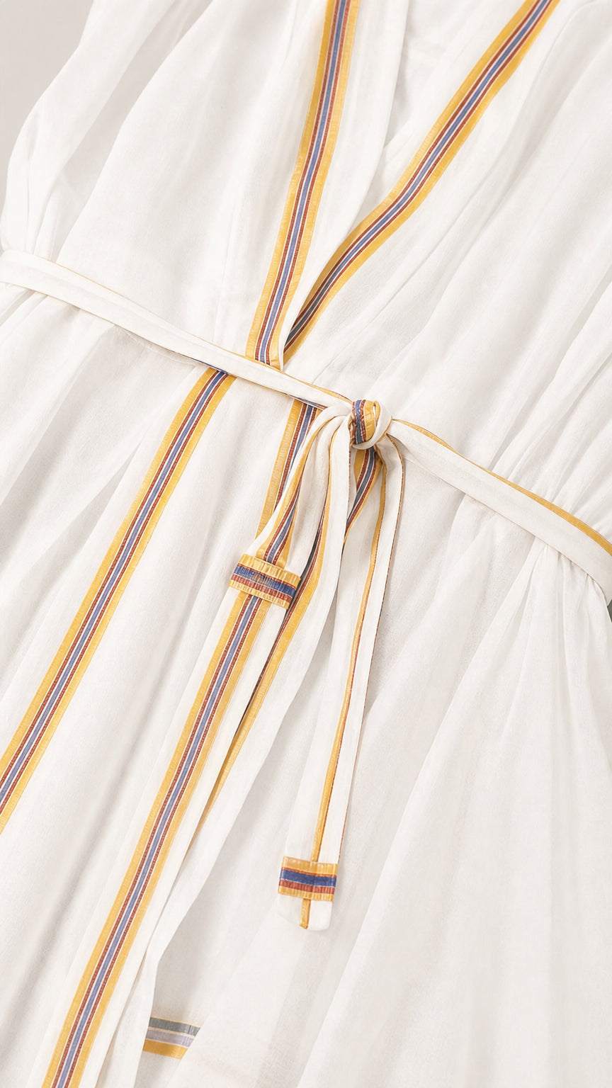 Close-up detail of contrast trim and waist tie on white romper