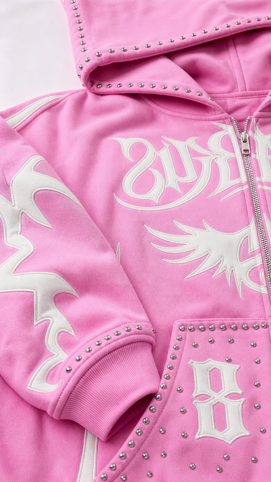 Close-up detail of rhinestone studs and white gothic prints on pink fleece hoodie