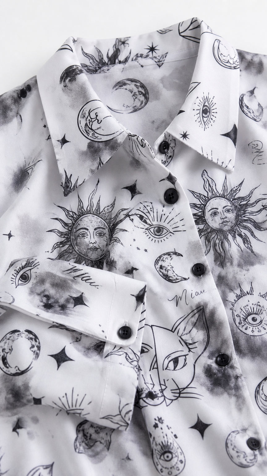 Close up detail of white fabric with celestial sun, moon, and cat graphic print and buttons