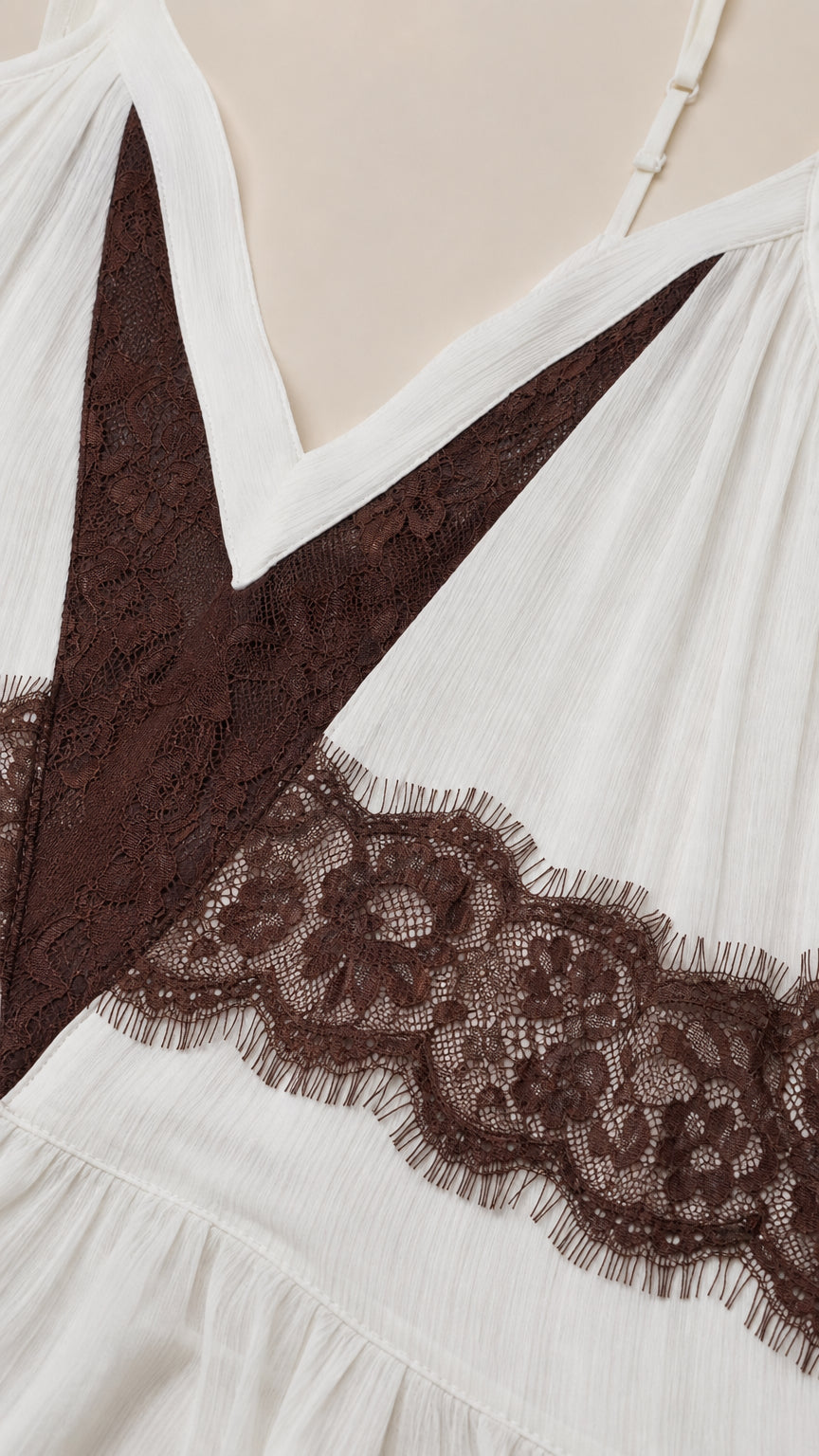 Close-up detail of textured white crinkle fabric and contrast brown eyelash lace
