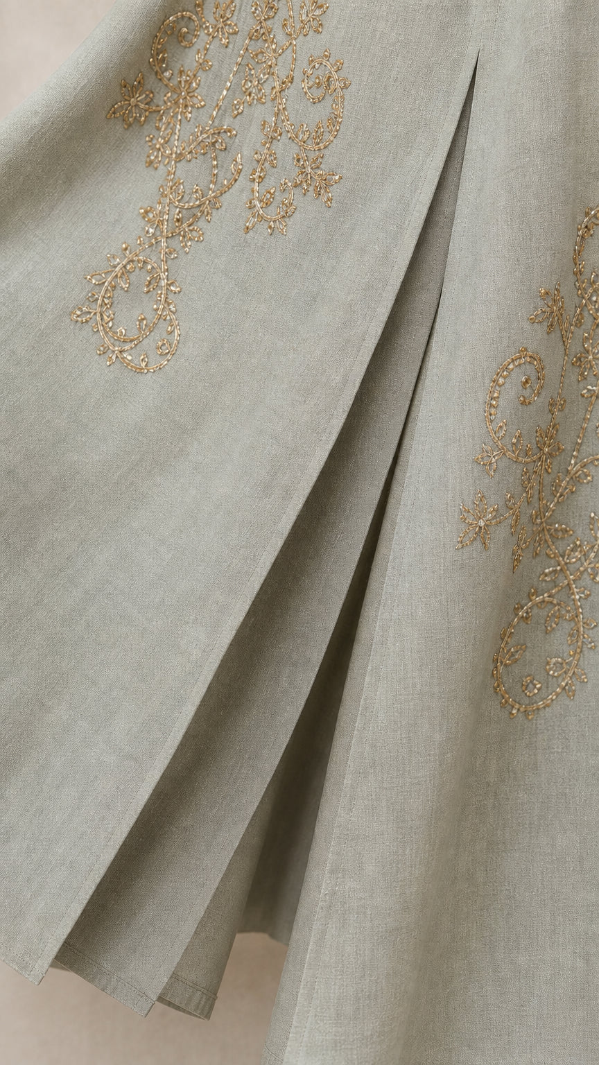 Close-up of gold-tone embroidery and pleat detail on hem
