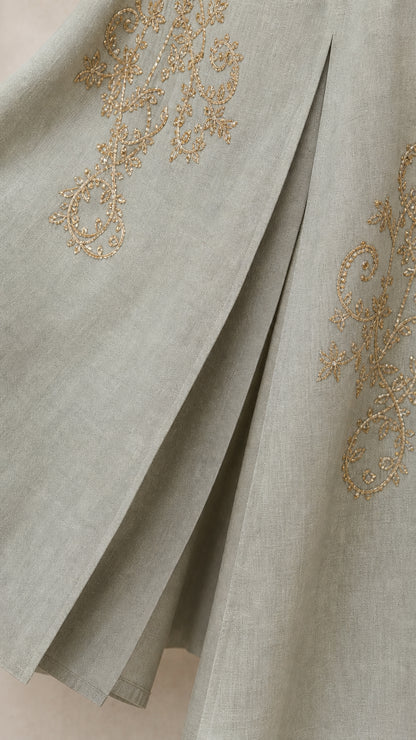 Close-up of gold-tone embroidery and pleat detail on hem