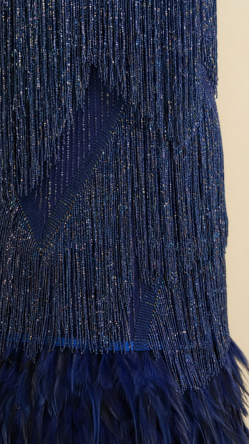 Close-up detail shot of the sequin texture, fringe, and feather hem on Navy dress
