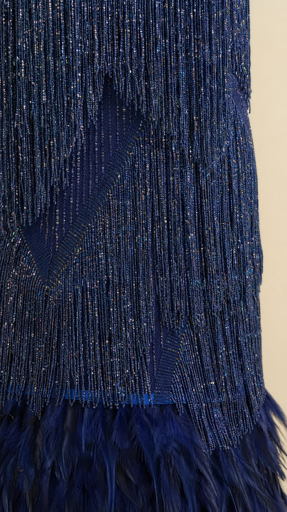 Close-up detail shot of the sequin texture, fringe, and feather hem on Navy dress
