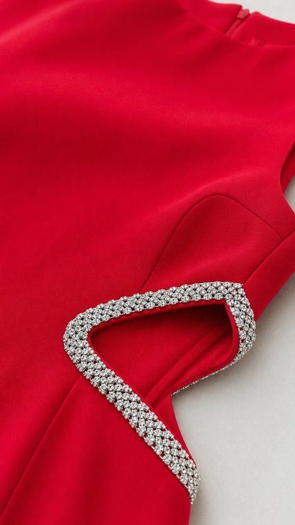 Close-up detail of rhinestone trim and waist cutout on red dress
