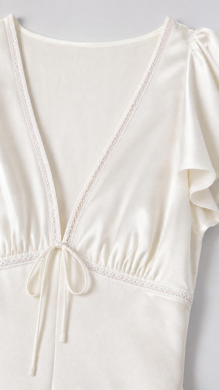 Close up of V-neckline and lace trim on white dress