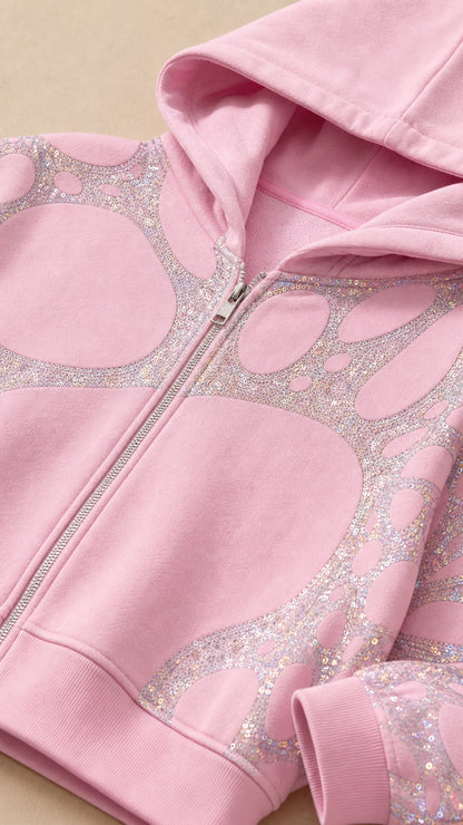 Close-up detail of rhinestone and glitter pattern on pink cropped zip hoodie