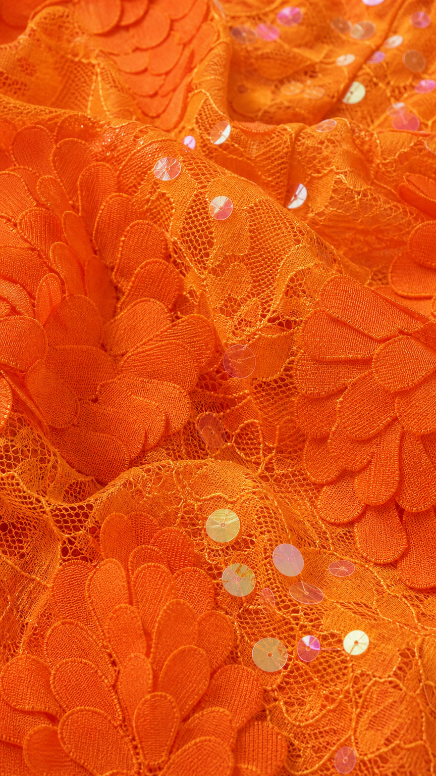 Close-up of orange sequin and floral lace fabric texture