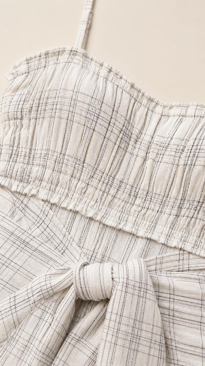 Close-up detail of smocked bodice and tie sash on white plaid dress