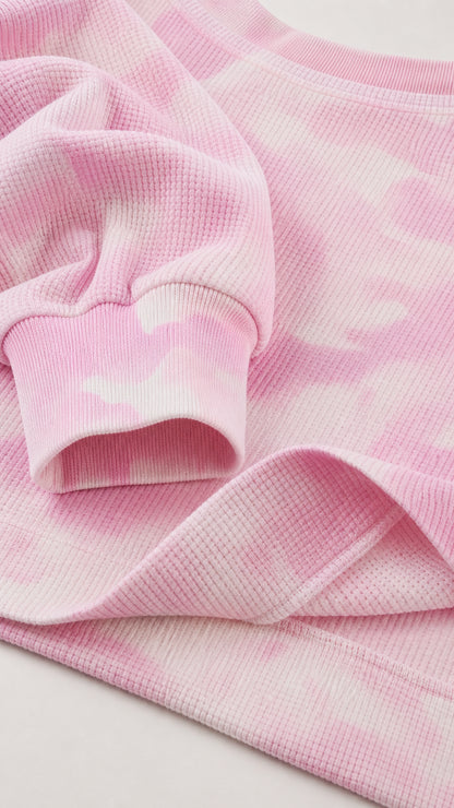 Close-up detail of pink waffle knit fabric, ribbed cuff, and stitched seam