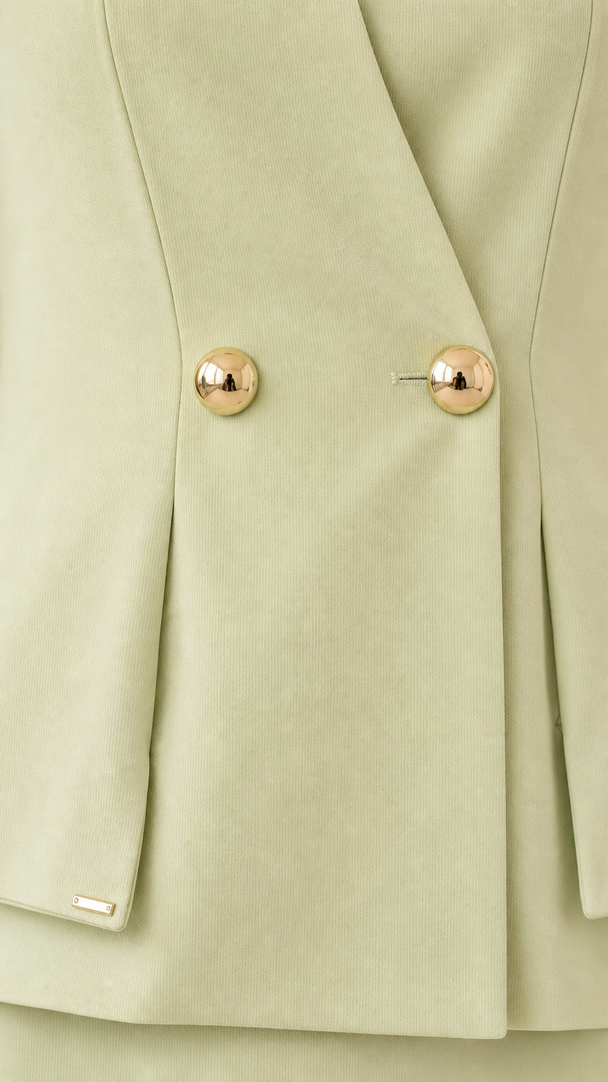 Close-up detail of textured fabric and gold-tone dome buttons on sage green peplum top