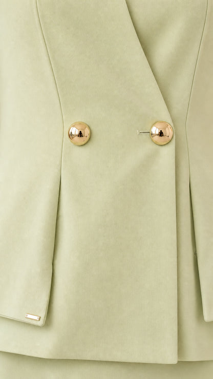 Close-up detail of textured fabric and gold-tone dome buttons on sage green peplum top