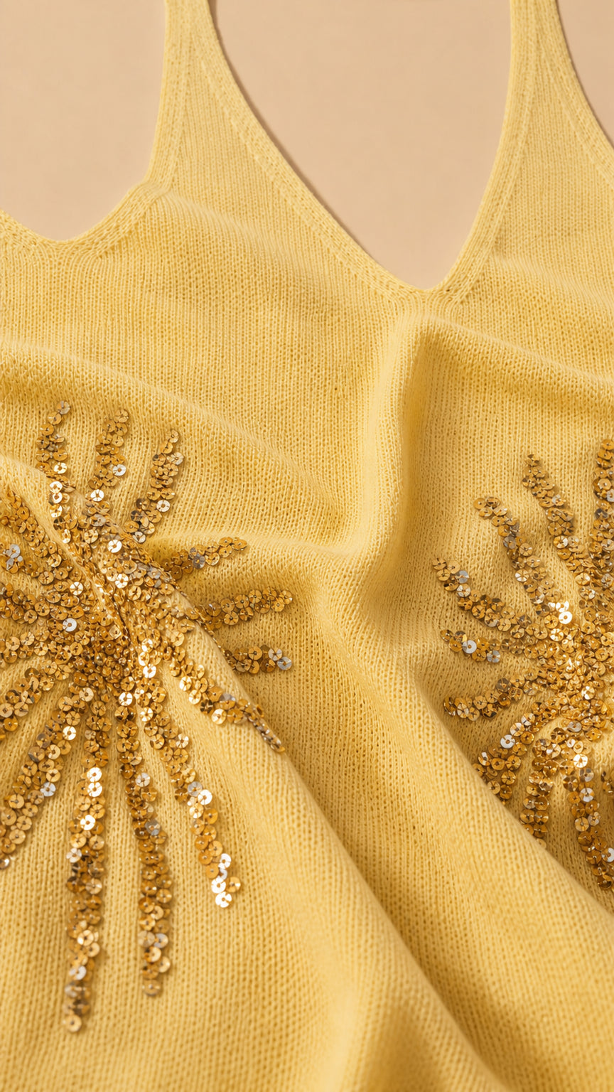 Close-up of yellow knit fabric texture and gold sequin sunburst embellishments