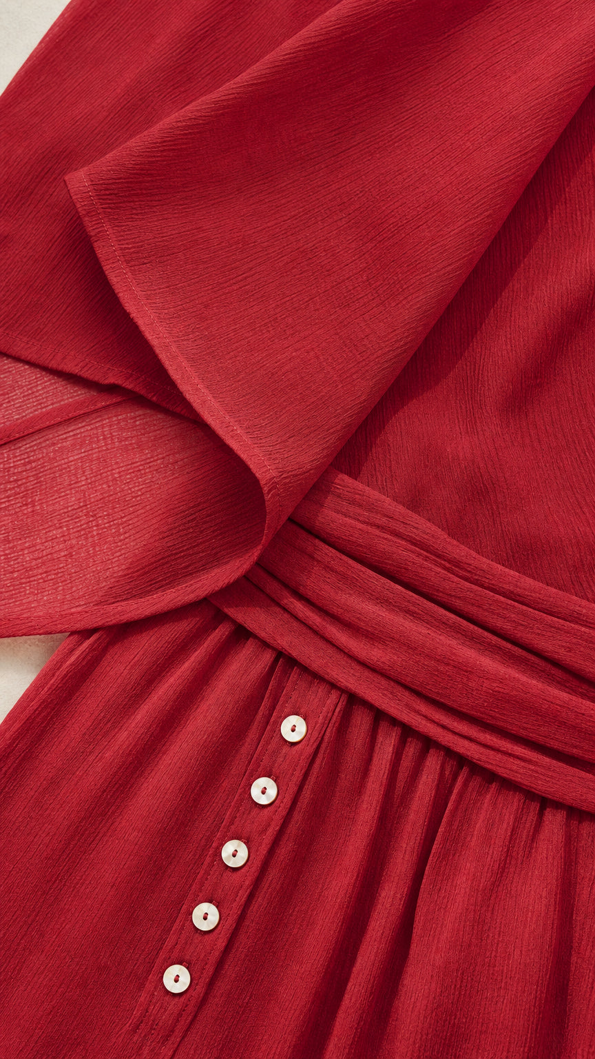 Close-up of red textured fabric, button details, and waistband