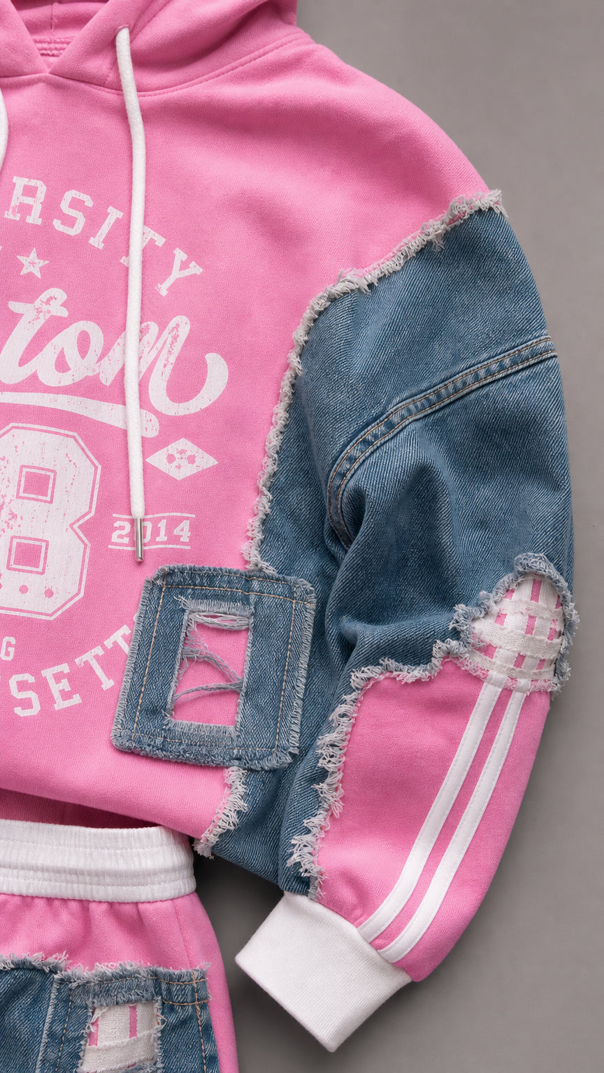 Close-up detail of distressed denim patchwork, fringe trim, and graphic print