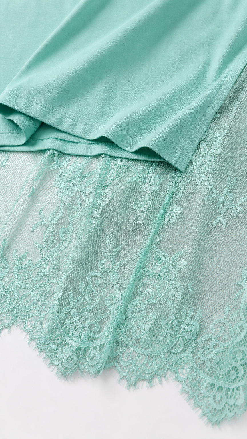 Close-up detail of mint green knit fabric hem and delicate floral eyelash lace