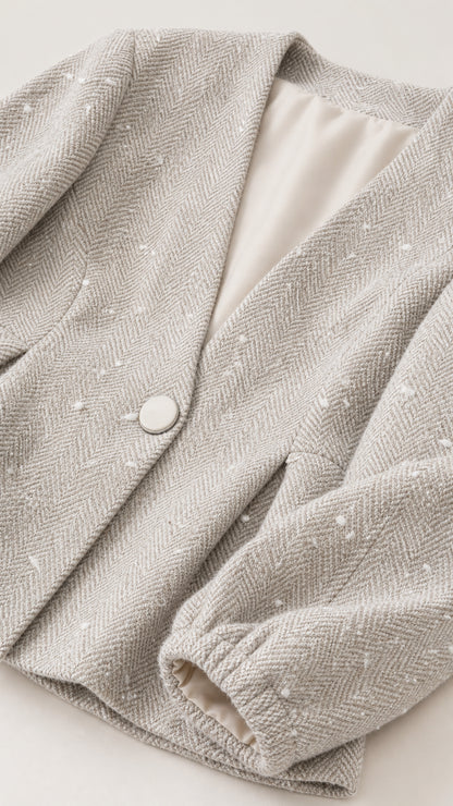 Close-up detail of textured fabric and button on beige blazer