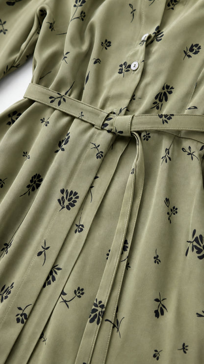 Close-up detail of buttons, belt, and floral pattern on sage green dress