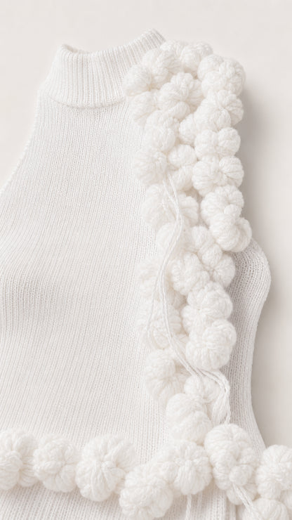Close-up detail of white ribbed knit fabric and textural yarn pom pom trim