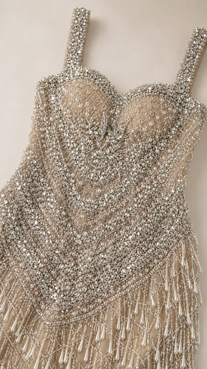 Close-up detail of champagne dress showing intricate pearls, sequins, and beaded fringe