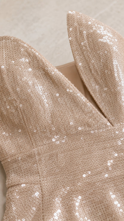 Close-up detail of shimmering champagne sequins and sculptural split neckline